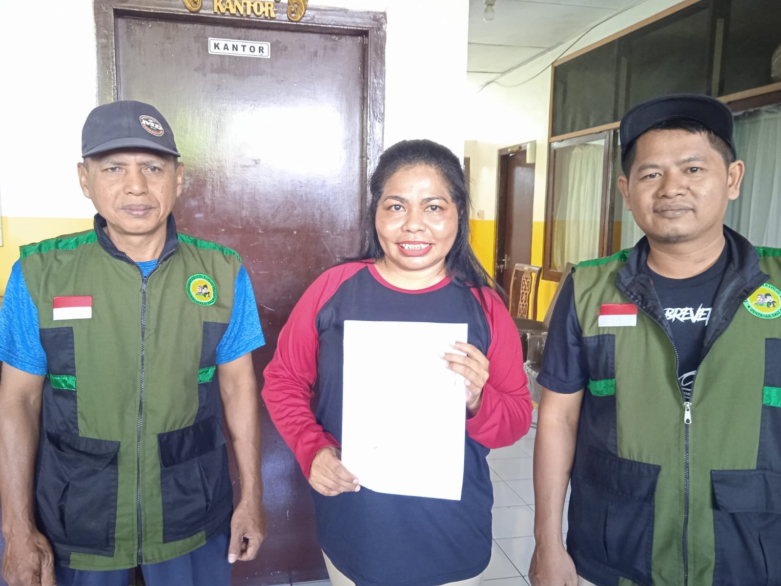 Dua relawan yayasan berfoto bersama seorang perempuan saat kunjungan.