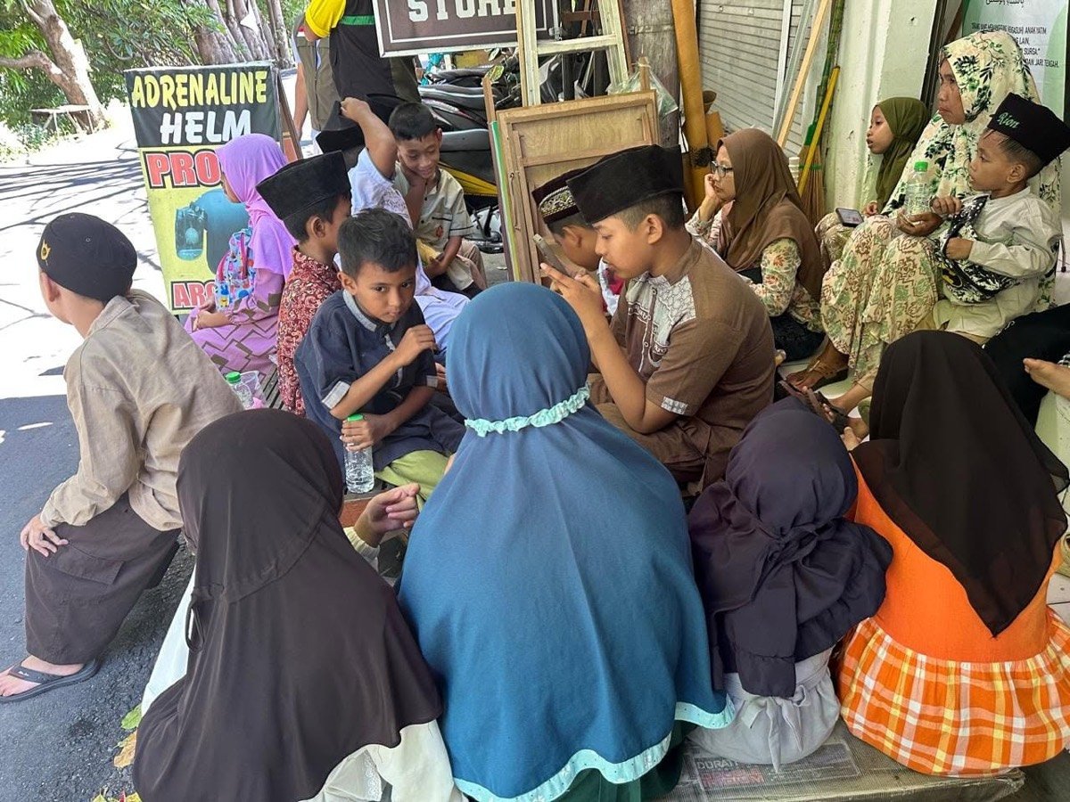 Anak-anak asuh duduk berkumpul di halaman bersama pendamping dalam kegiatan yayasan.